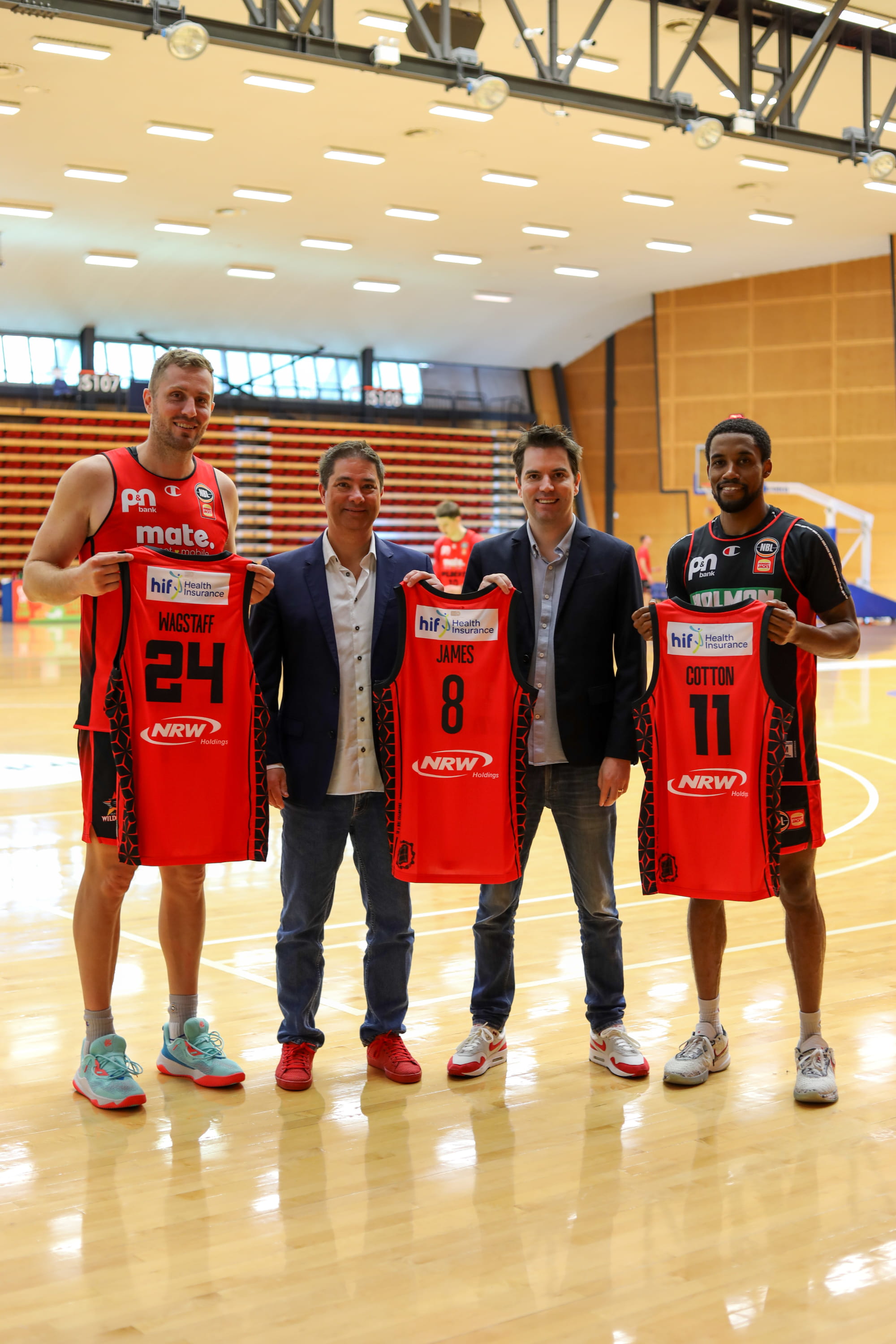 Justin James, CEO of HIF standing with the coach and two Perth Wildcats basketball players and holding up team jersey