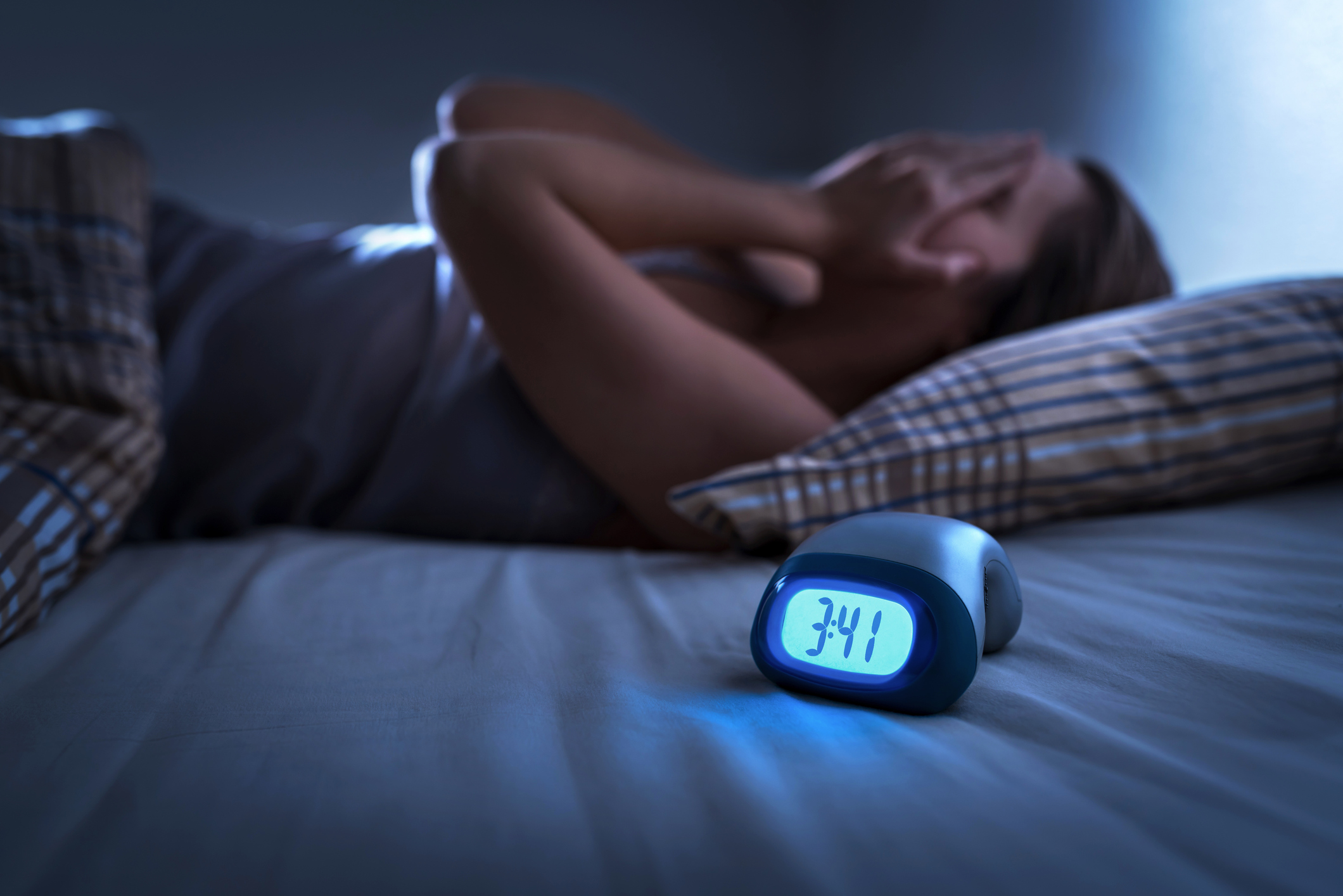  Person lying awake in bed at 3:41 AM, covering their eyes with their hands, with an alarm clock displaying the time.